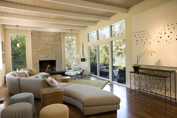 This is an example of an expansive eclectic open plan living room in San Francisco with white walls, medium hardwood flooring, a standard fireplace and a stone fireplace surround.