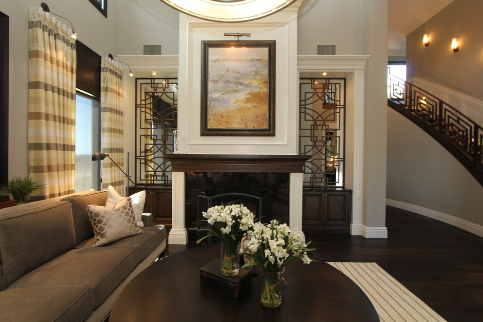Пример оригинального дизайна: гостиная комната в классическом стиле с темным паркетным полом, стандартным камином и коричневым диваном