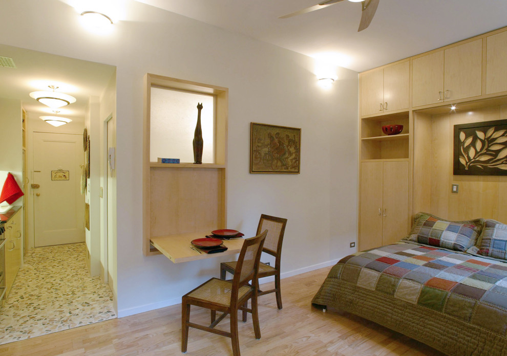 Modelo de salón abierto actual pequeño con paredes beige, suelo de madera clara y pared multimedia