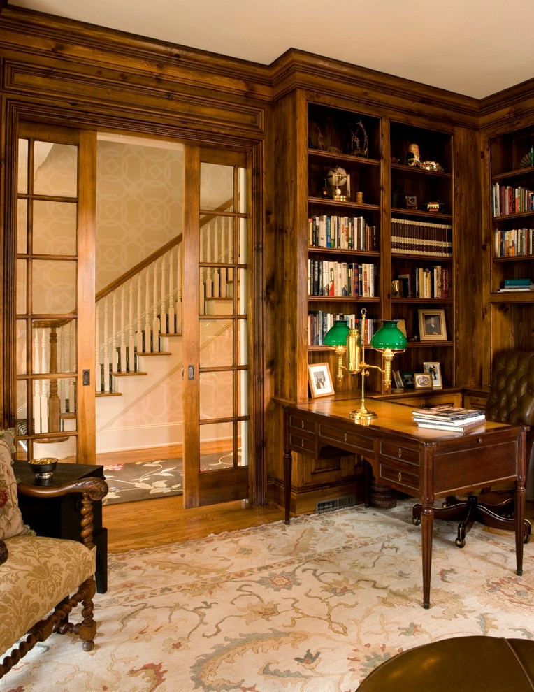 Ejemplo de despacho sin chimenea con biblioteca y suelo de madera en tonos medios