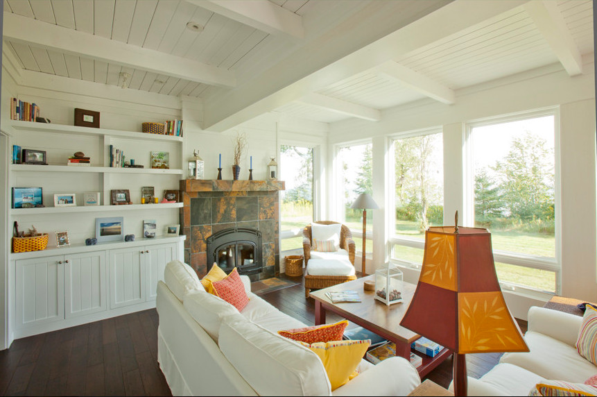 This is an example of a small beach style open plan living room in Other with white walls, dark hardwood flooring, a standard fireplace, a stone fireplace surround and brown floors.