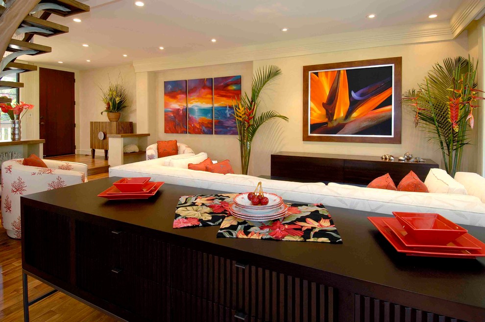 Foto di un soggiorno tropicale aperto con pareti beige, pavimento in legno massello medio e TV nascosta