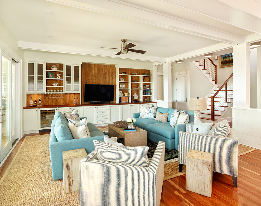 Cette image montre un salon marin de taille moyenne et ouvert avec un bar de salon, un sol en bois brun et un téléviseur encastré.