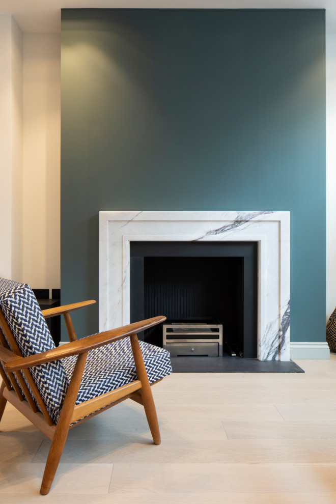 This is an example of a medium sized modern open plan living room in London with green walls, light hardwood flooring, a standard fireplace and a stone fireplace surround.