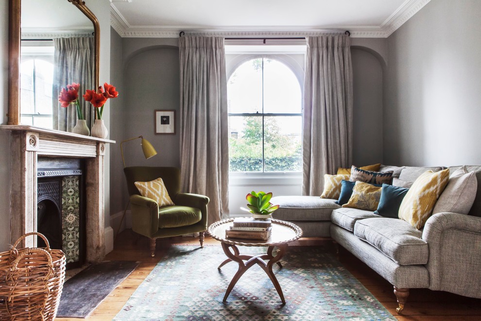 Пример оригинального дизайна: парадная гостиная комната в классическом стиле с серыми стенами, светлым паркетным полом, стандартным камином и ковром на полу без телевизора