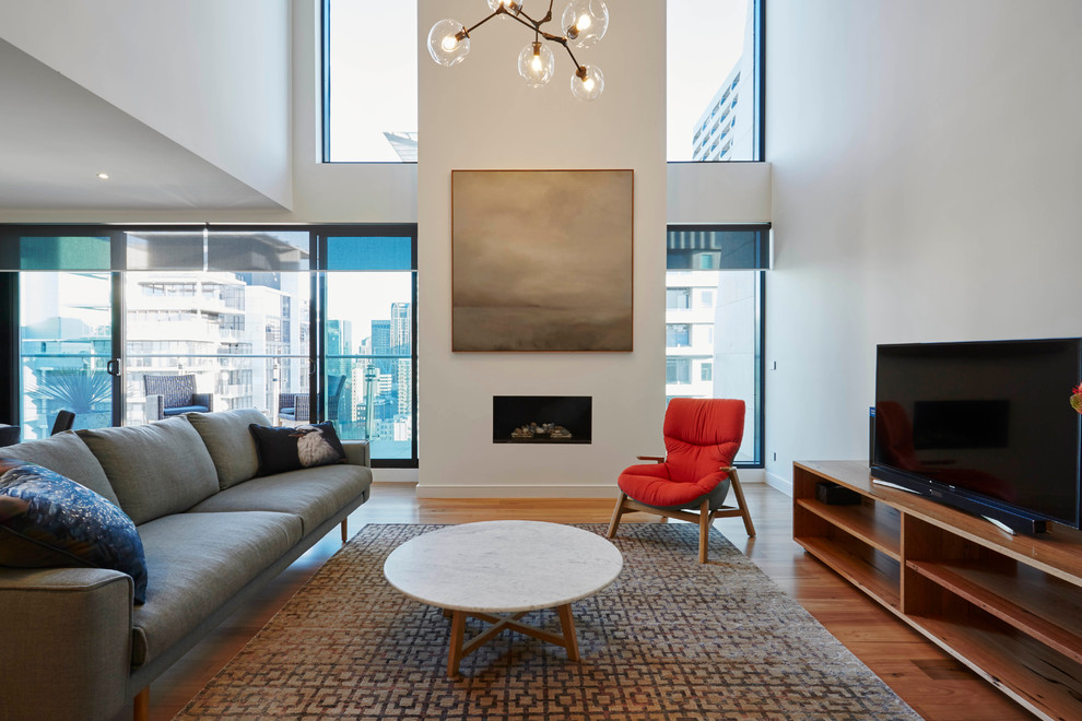 Kleines, Repräsentatives Modernes Wohnzimmer im Loft-Stil mit weißer Wandfarbe, braunem Holzboden, verputzter Kaminumrandung und freistehendem TV in Melbourne