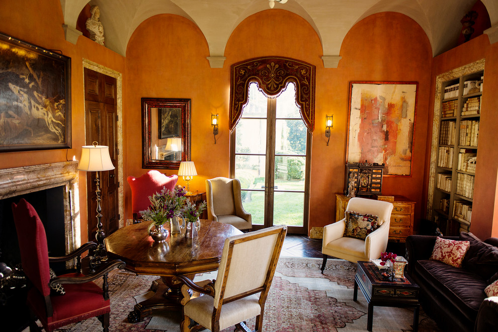 Стильный дизайн: большая изолированная гостиная комната в средиземноморском стиле с с книжными шкафами и полками, темным паркетным полом, стандартным камином, фасадом камина из камня и оранжевыми стенами - последний тренд