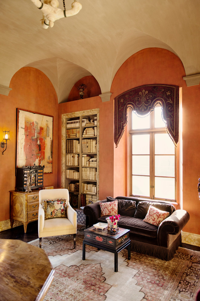 Ejemplo de biblioteca en casa cerrada mediterránea grande con parades naranjas, suelo de madera oscura, todas las chimeneas y marco de chimenea de piedra