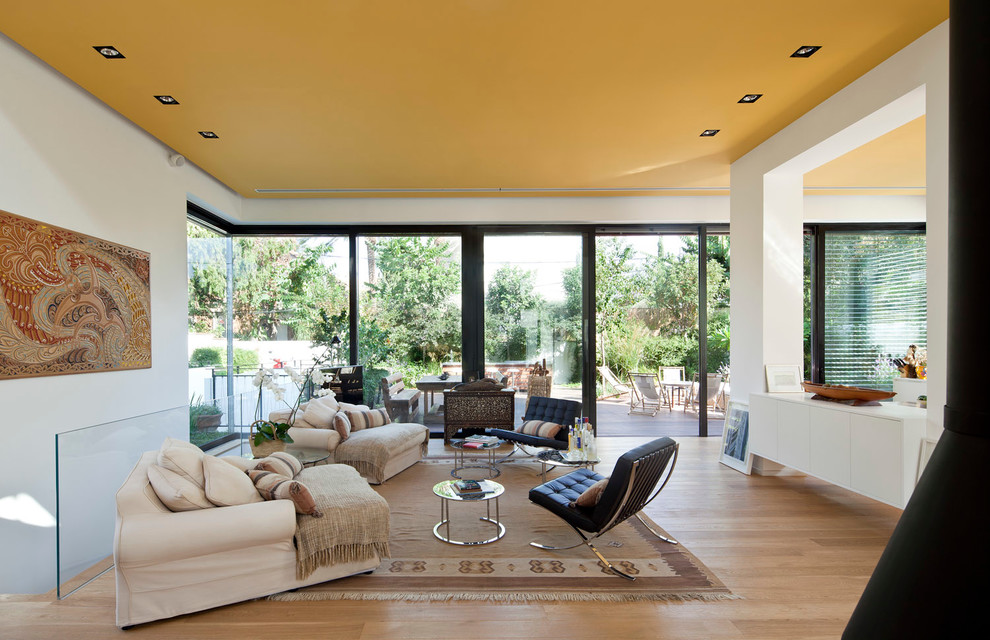 This is an example of a world-inspired living room in Tel Aviv with white walls and light hardwood flooring.