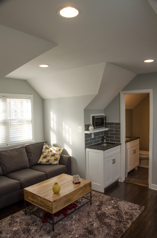 Cette photo montre un petit salon mansardé ou avec mezzanine chic avec un mur gris, parquet foncé, une cheminée standard, un téléviseur encastré et un sol marron.