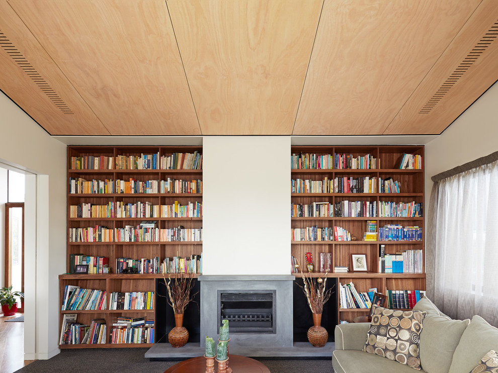 Exemple d'un grand salon tendance ouvert avec une bibliothèque ou un coin lecture, un mur gris, moquette, une cheminée standard et un manteau de cheminée en béton.
