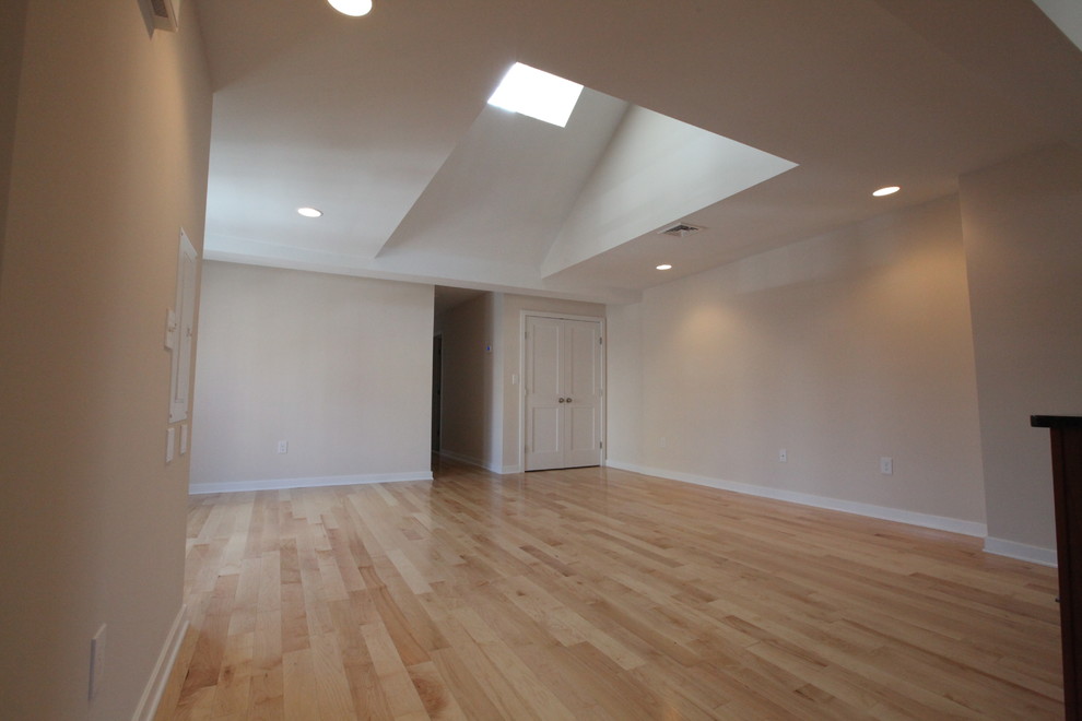 Expansive contemporary open plan living room in Philadelphia with white walls and light hardwood flooring.