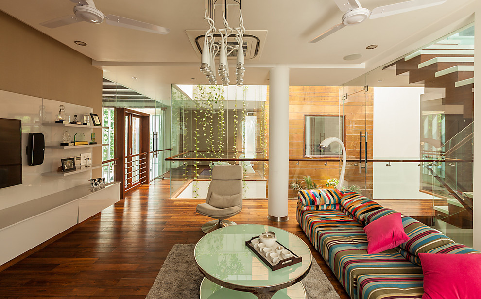 Immagine di un soggiorno design aperto con pareti marroni, pavimento in legno massello medio e TV a parete