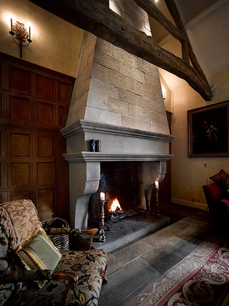 チェシャーにあるラグジュアリーな広いトラディショナルスタイルのおしゃれなリビング (黄色い壁、スレートの床、標準型暖炉、石材の暖炉まわり、テレビなし) の写真