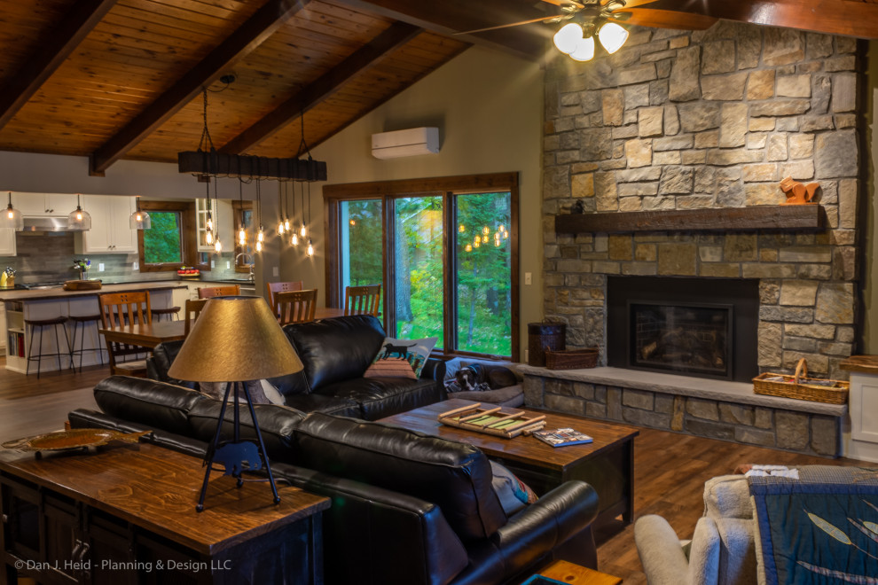Medium sized rustic open plan living room in Minneapolis with beige walls, medium hardwood flooring, a standard fireplace, a stone fireplace surround, a freestanding tv and brown floors.