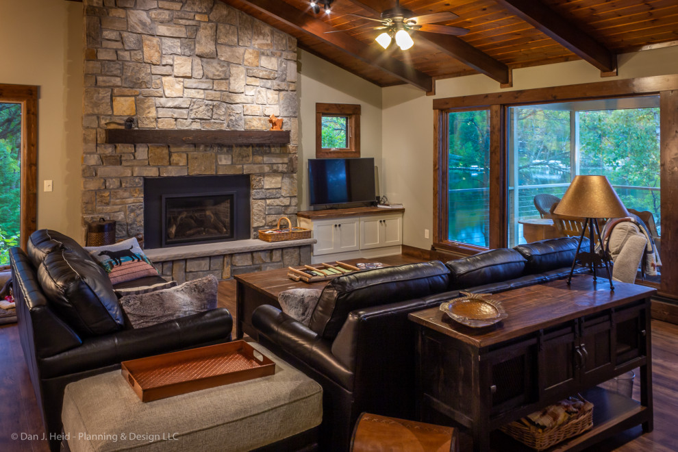 Medium sized rustic open plan living room in Minneapolis with beige walls, medium hardwood flooring, a standard fireplace, a stone fireplace surround, a freestanding tv and brown floors.