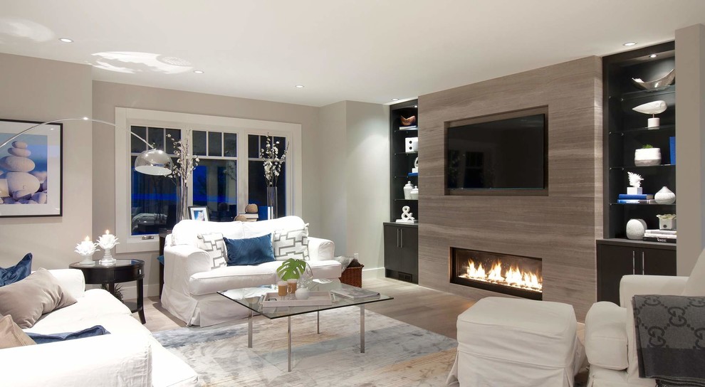 На фото: открытая гостиная комната среднего размера в современном стиле с серыми стенами, полом из керамогранита, стандартным камином, фасадом камина из камня и телевизором на стене