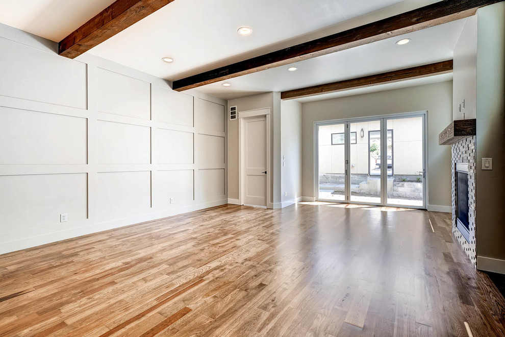Immagine di un grande soggiorno minimalista aperto con pareti beige, pavimento in legno massello medio e camino classico