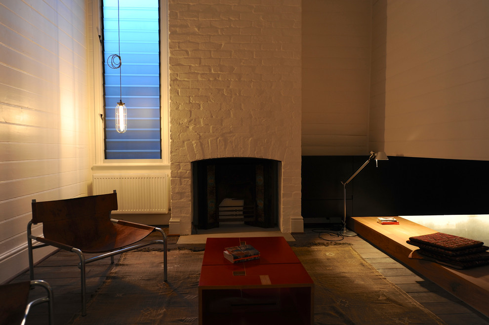 Imagen de salón para visitas abierto minimalista con paredes blancas, suelo de madera en tonos medios, todas las chimeneas, marco de chimenea de ladrillo y suelo blanco