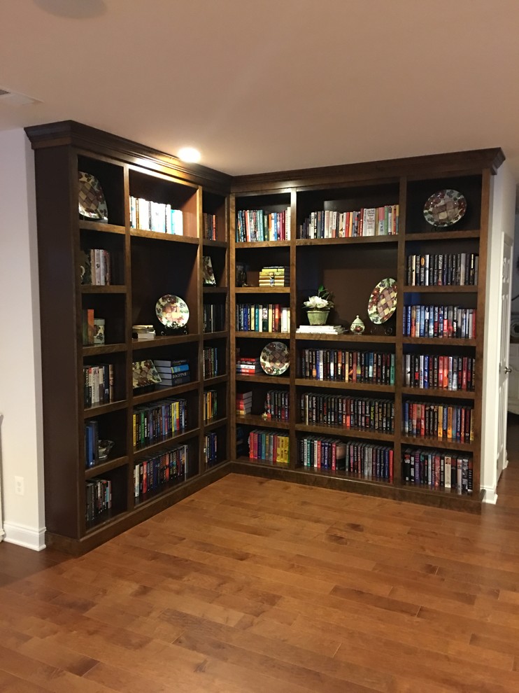 Imagen de biblioteca en casa abierta tradicional de tamaño medio sin chimenea y televisor con paredes blancas, suelo de madera en tonos medios y suelo marrón
