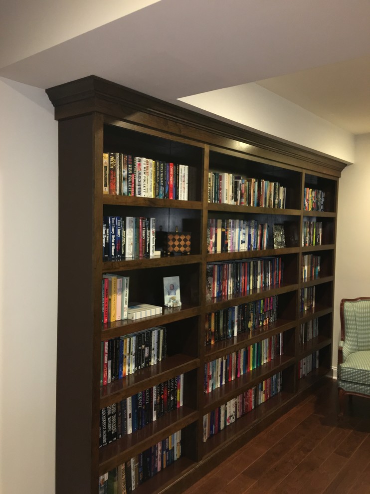 Example of a mid-sized classic open concept medium tone wood floor and brown floor living room library design in DC Metro with white walls, no fireplace and no tv