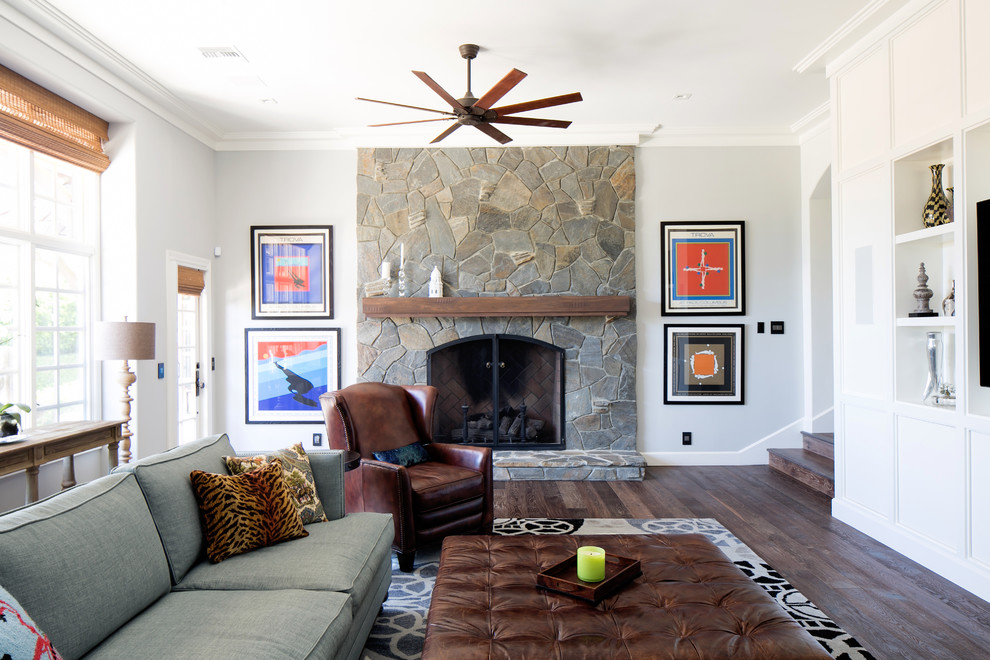 Klassisches Wohnzimmer mit weißer Wandfarbe, dunklem Holzboden, Kamin, Kaminumrandung aus Stein und Multimediawand in Orange County