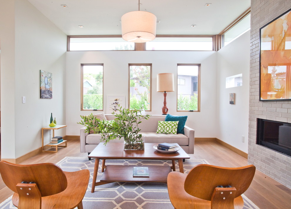 Example of a trendy medium tone wood floor living room design in Los Angeles with white walls and a ribbon fireplace
