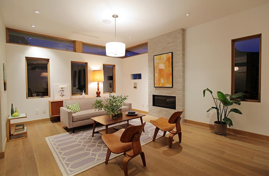 Esempio di un grande soggiorno moderno aperto con sala formale, pareti bianche, pavimento in legno massello medio, camino classico e cornice del camino in mattoni