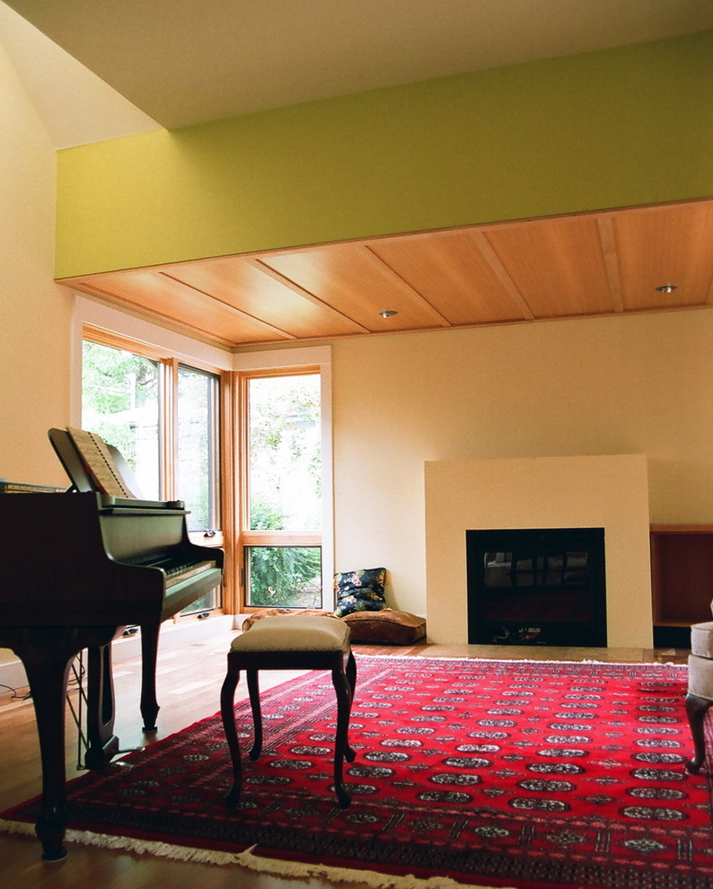Foto de salón abierto contemporáneo de tamaño medio con paredes amarillas, suelo de madera clara y todas las chimeneas