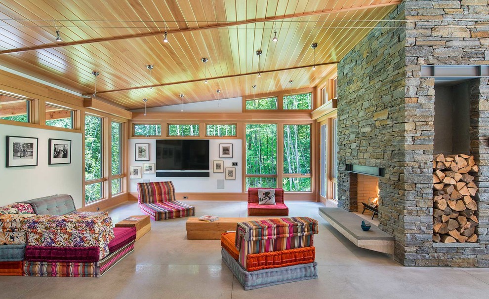 Inspiration for a contemporary open concept concrete floor and gray floor living room remodel in Burlington with white walls, a standard fireplace, a stone fireplace and a wall-mounted tv