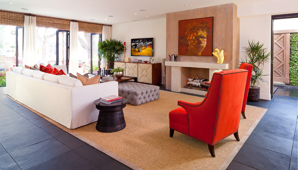 Идея дизайна: открытая гостиная комната среднего размера в стиле фьюжн с стандартным камином, телевизором на стене, полом из сланца, белыми стенами, фасадом камина из камня, черным полом и ковром на полу