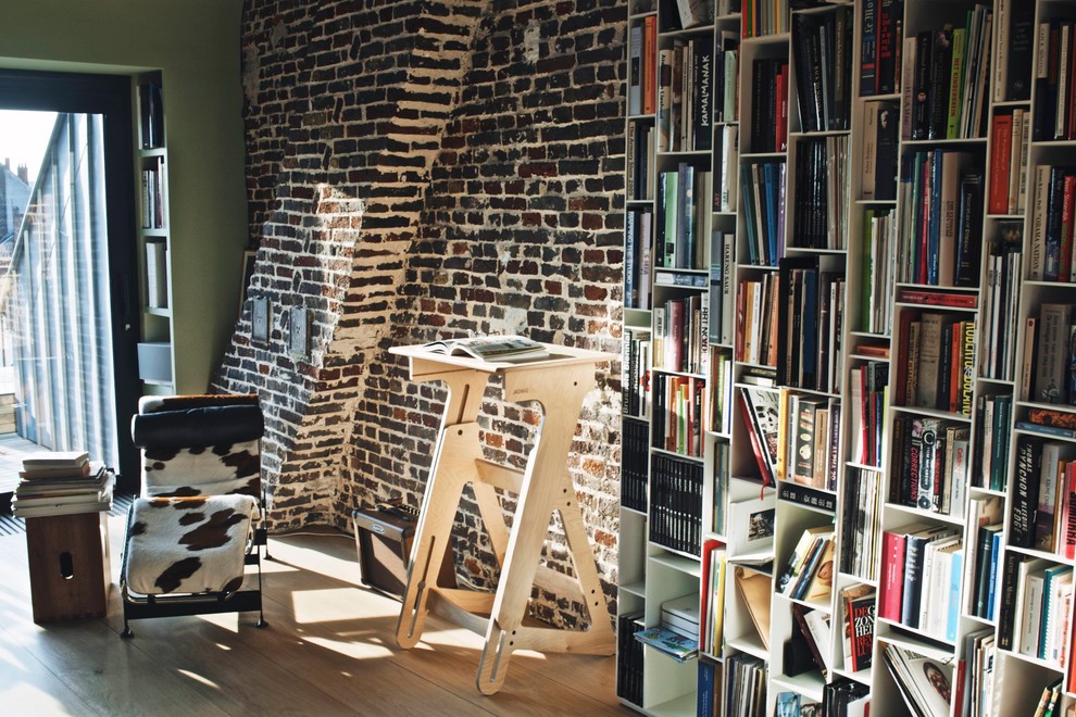 Bild på ett litet 60 tals loftrum, med ett bibliotek, gröna väggar och ljust trägolv