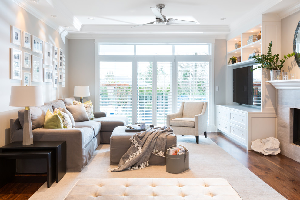 Living room - mid-sized contemporary open concept medium tone wood floor living room idea in Vancouver with gray walls, a standard fireplace, a tile fireplace and a media wall