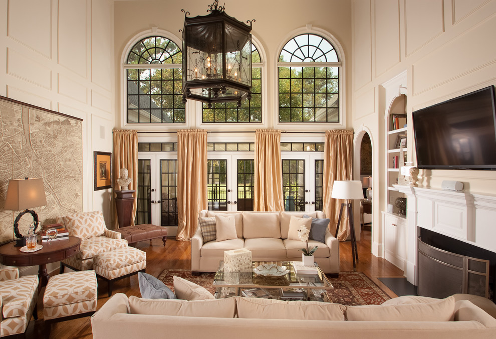 Großes Klassisches Wohnzimmer mit beiger Wandfarbe, Kamin, verputzter Kaminumrandung, TV-Wand, braunem Holzboden und braunem Boden in Atlanta