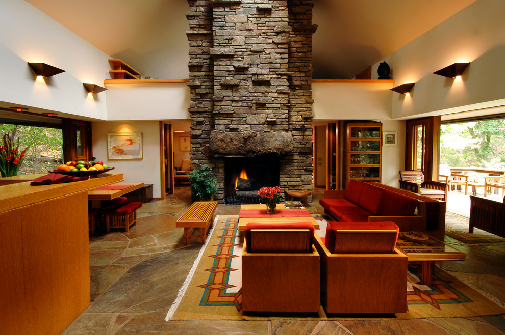 Стильный дизайн: большая открытая гостиная комната в современном стиле с стандартным камином, фасадом камина из камня, белыми стенами, полом из сланца и коричневым полом без телевизора - последний тренд