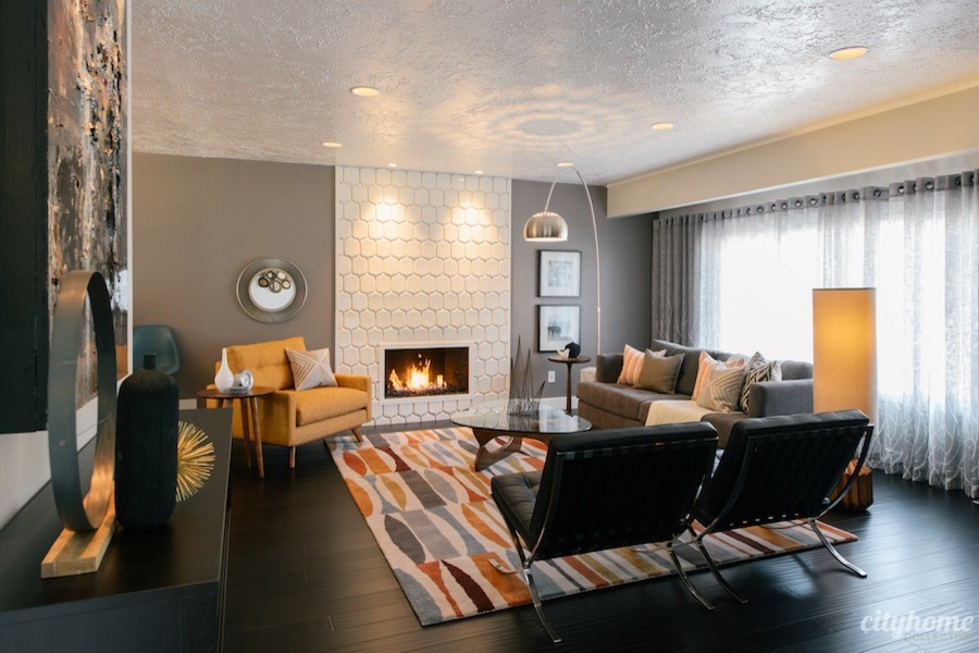 Стильный дизайн: открытая гостиная комната среднего размера в стиле ретро с серыми стенами, темным паркетным полом, стандартным камином и фасадом камина из плитки - последний тренд