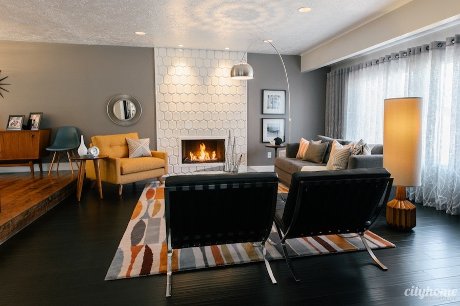 На фото: открытая гостиная комната среднего размера в стиле ретро с серыми стенами, темным паркетным полом, стандартным камином и фасадом камина из плитки