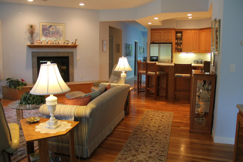 Cette image montre un salon traditionnel de taille moyenne et ouvert avec un sol en bois brun, un mur bleu, une cheminée standard, un manteau de cheminée en carrelage et un téléviseur encastré.