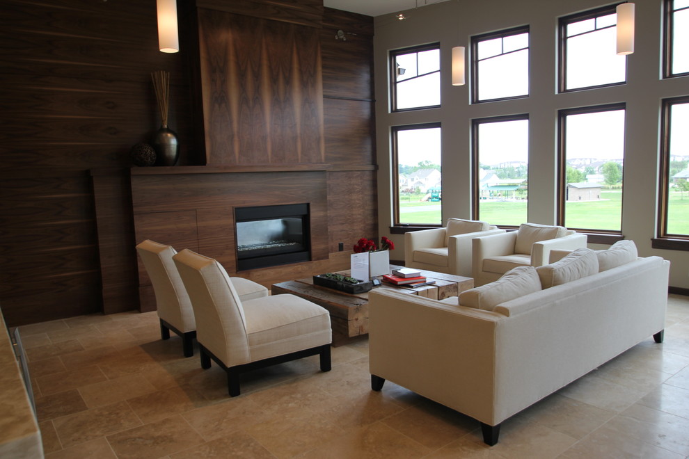 На фото: гостиная комната в современном стиле с фасадом камина из дерева, стандартным камином и полом из травертина с