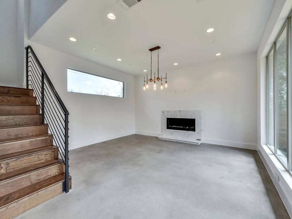 Großes, Repräsentatives, Fernseherloses, Abgetrenntes Modernes Wohnzimmer ohne Kamin mit weißer Wandfarbe, Betonboden, grauem Boden und Kaminumrandung aus Stein in Austin