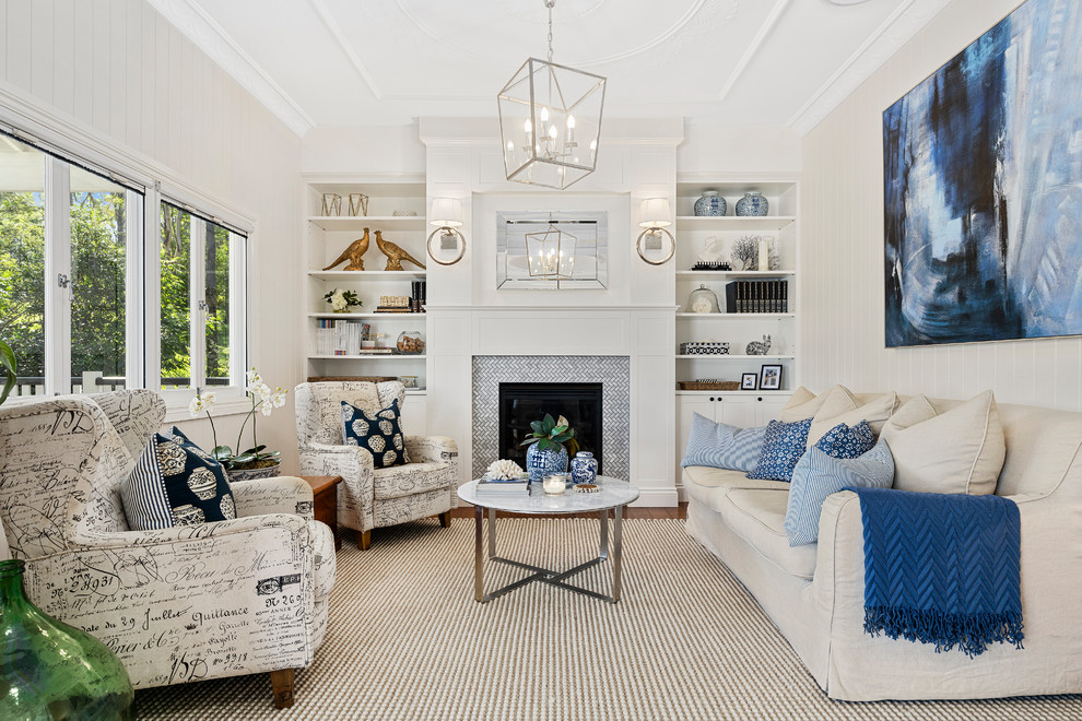 Repräsentatives, Fernseherloses Klassisches Wohnzimmer mit weißer Wandfarbe, braunem Holzboden, Kamin, gefliester Kaminumrandung und braunem Boden in Brisbane