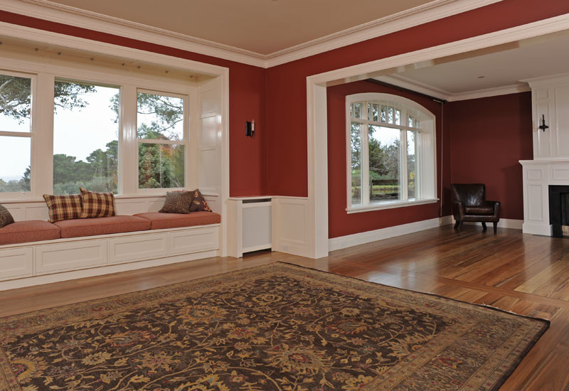 Идея дизайна: огромная открытая гостиная комната в классическом стиле с красными стенами, паркетным полом среднего тона, стандартным камином и фасадом камина из дерева