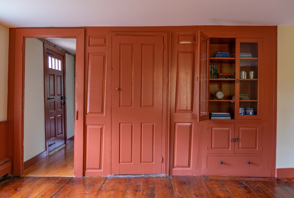 Mittelgroßes, Repräsentatives, Fernseherloses, Abgetrenntes Landhaus Wohnzimmer ohne Kamin mit roter Wandfarbe und braunem Holzboden in Boston