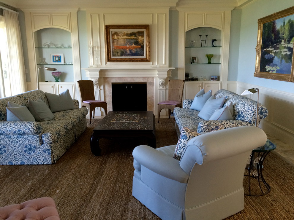 На фото: гостиная комната в стиле неоклассика (современная классика) с синими стенами, мраморным полом, стандартным камином и фасадом камина из дерева с