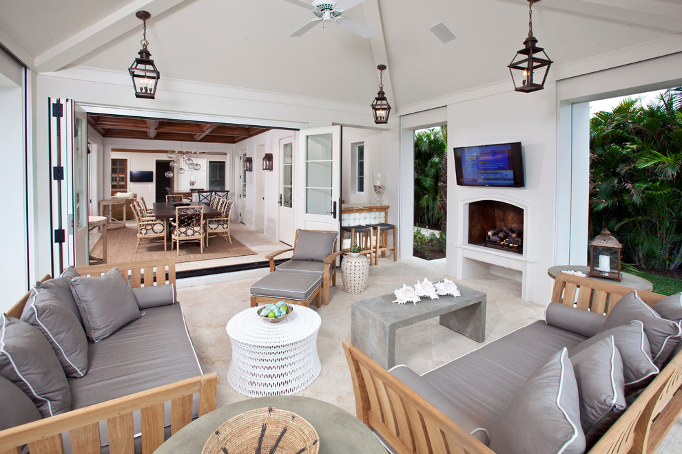 Immagine di un soggiorno tropicale con pareti bianche, camino classico e TV a parete