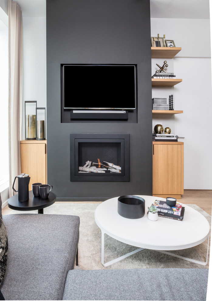 This is an example of a contemporary living room in New York with light hardwood flooring, a standard fireplace, a built-in media unit and black walls.