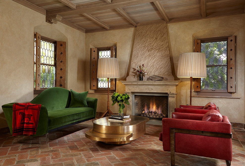 На фото: гостиная комната в средиземноморском стиле с бежевыми стенами, кирпичным полом, стандартным камином и красным полом с
