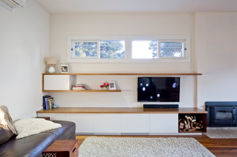 Стильный дизайн: гостиная комната среднего размера в современном стиле с белыми стенами, светлым паркетным полом, стандартным камином, фасадом камина из кирпича и телевизором на стене - последний тренд