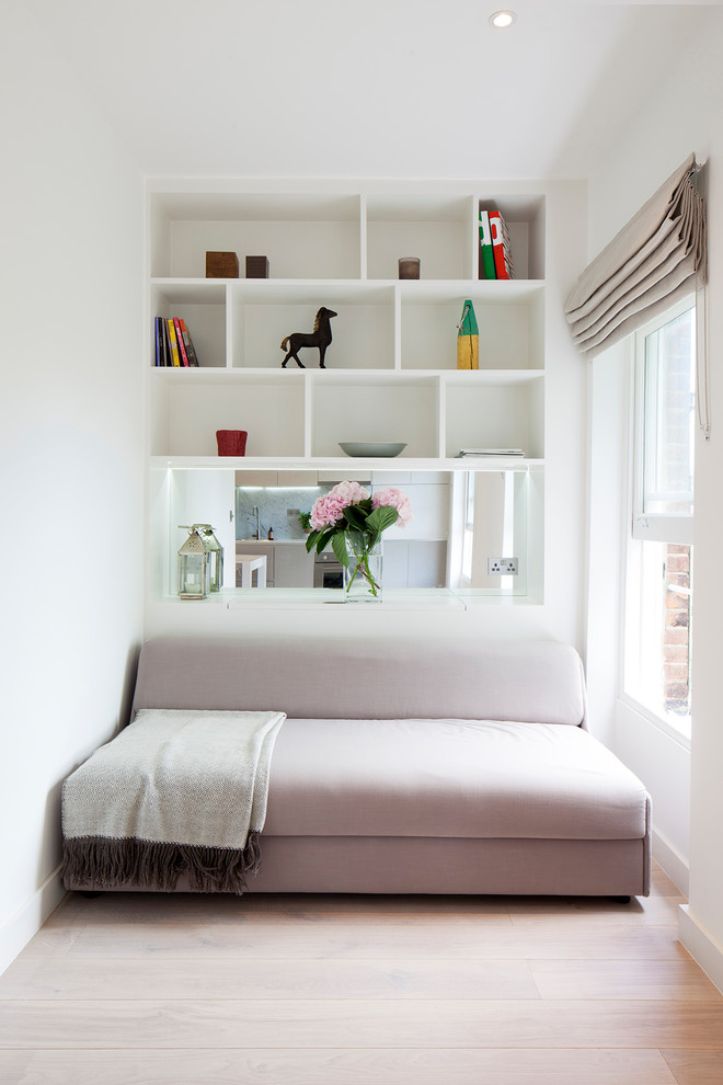 Cette photo montre un petit salon tendance avec un mur blanc, parquet clair, une bibliothèque ou un coin lecture et un sol beige.