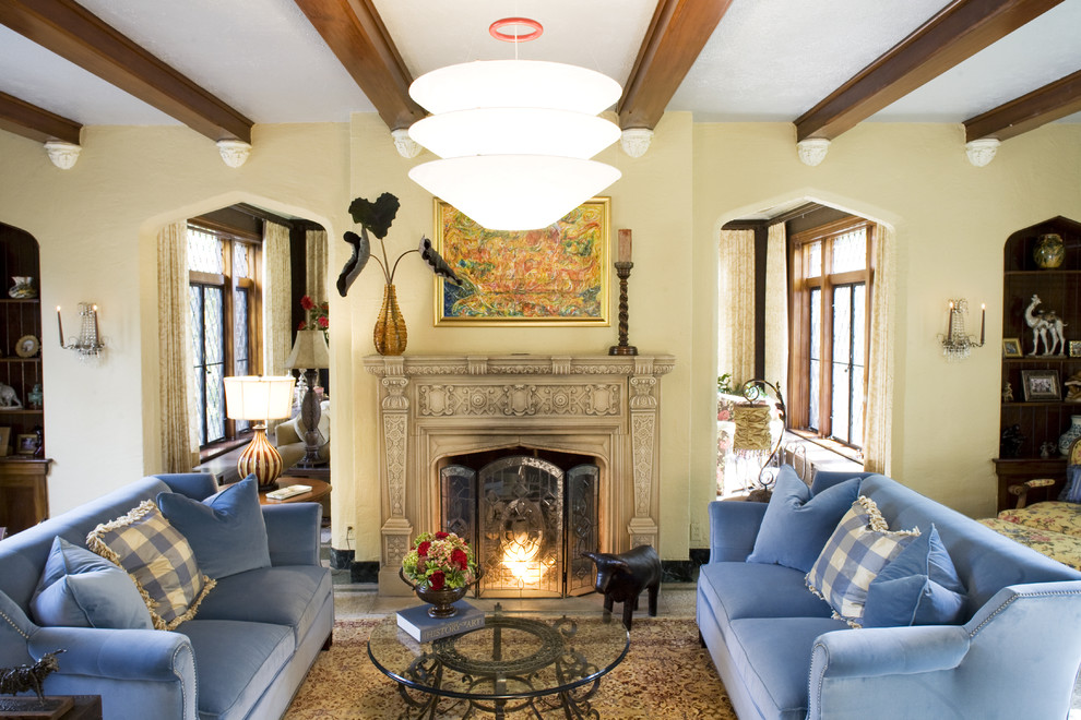 セントルイスにある高級な広いトラディショナルスタイルのおしゃれな独立型リビング (ベージュの壁、標準型暖炉、トラバーチンの床、石材の暖炉まわり、ベージュの床、青いソファ) の写真